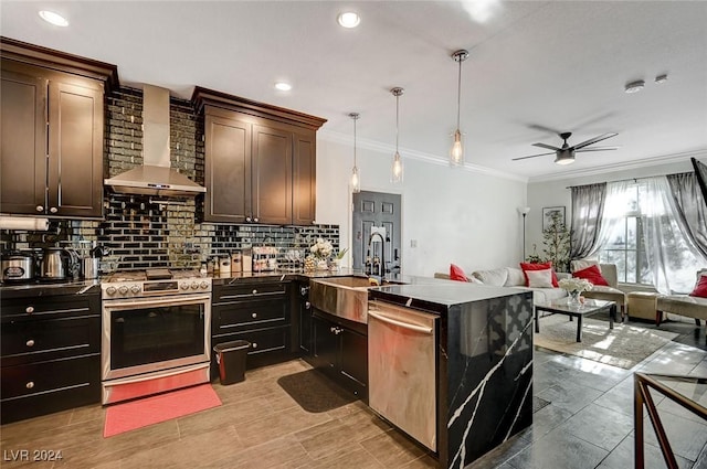 kitchen featuring stainless steel appliances, ceiling fan, sink, wall chimney range hood, and hanging light fixtures