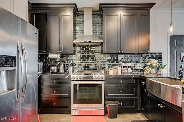 kitchen with wall chimney range hood, appliances with stainless steel finishes, tasteful backsplash, decorative light fixtures, and dark brown cabinetry