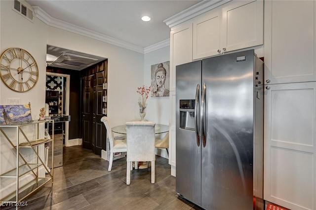 kitchen with stainless steel fridge, white cabinetry, and crown molding