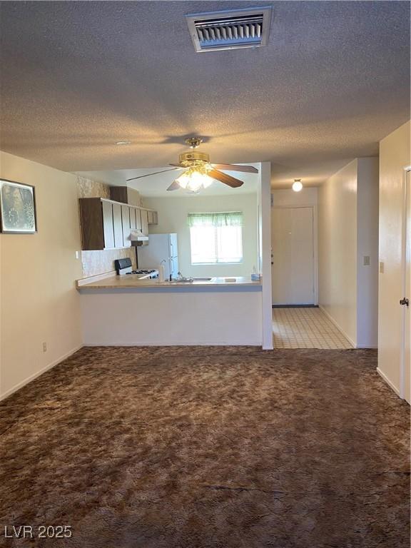 unfurnished living room with ceiling fan, light carpet, and a textured ceiling