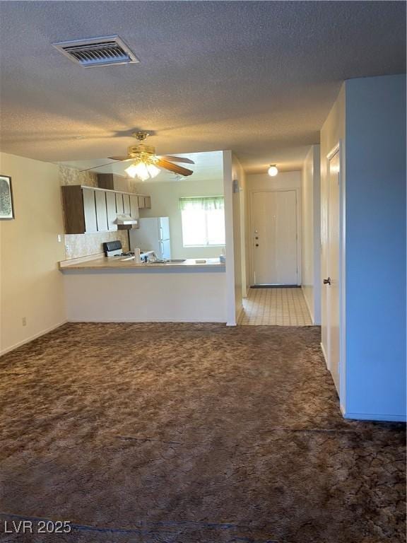 unfurnished living room featuring ceiling fan, carpet floors, and a textured ceiling