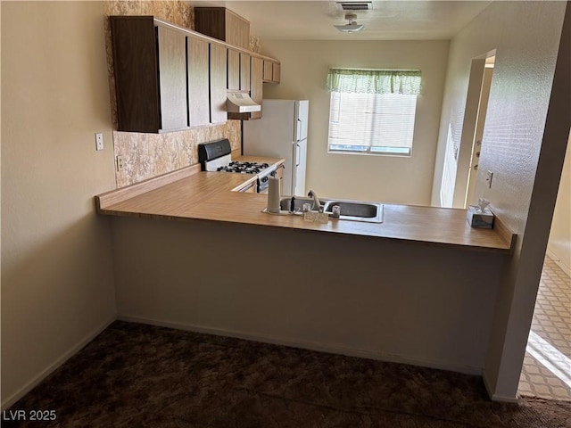 kitchen with white refrigerator, gas range oven, sink, and kitchen peninsula