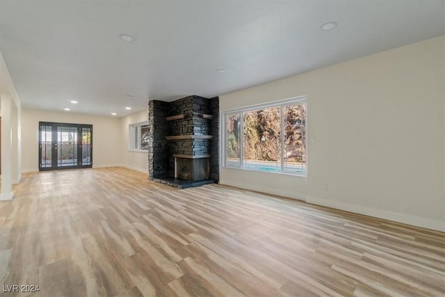 unfurnished living room with light hardwood / wood-style floors and a stone fireplace