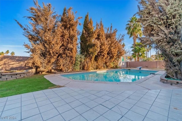 view of swimming pool with a diving board, a yard, and a patio