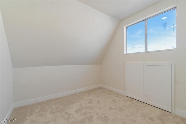 bonus room with light carpet and vaulted ceiling