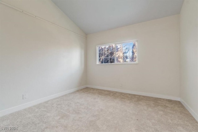 carpeted empty room featuring vaulted ceiling