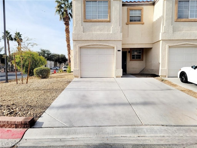 view of front of home with a garage, concrete driveway, and stucco siding