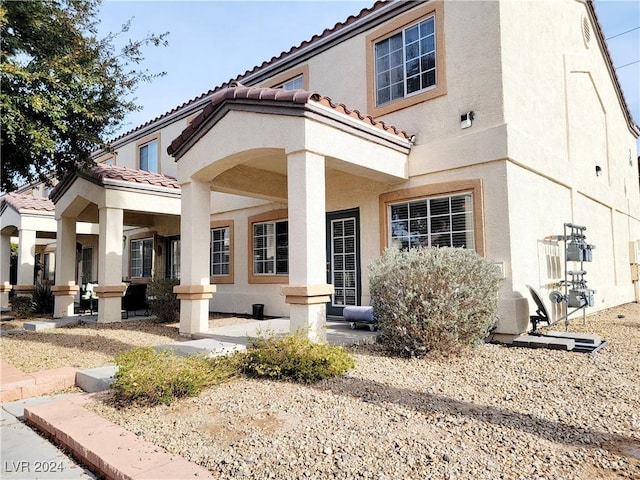 back of property featuring a tile roof and stucco siding