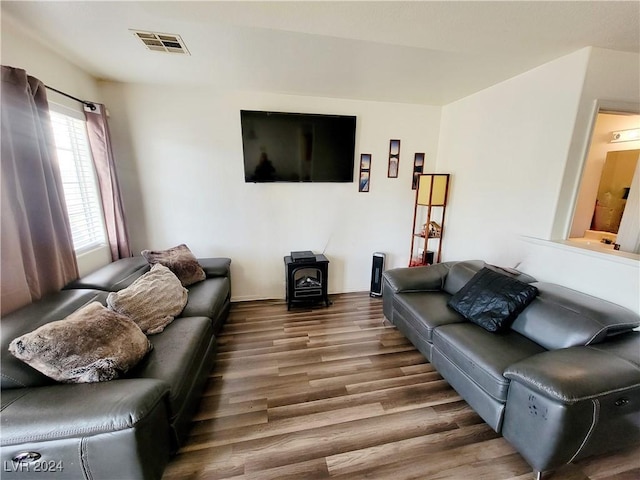 living room featuring a wood stove, visible vents, and wood finished floors