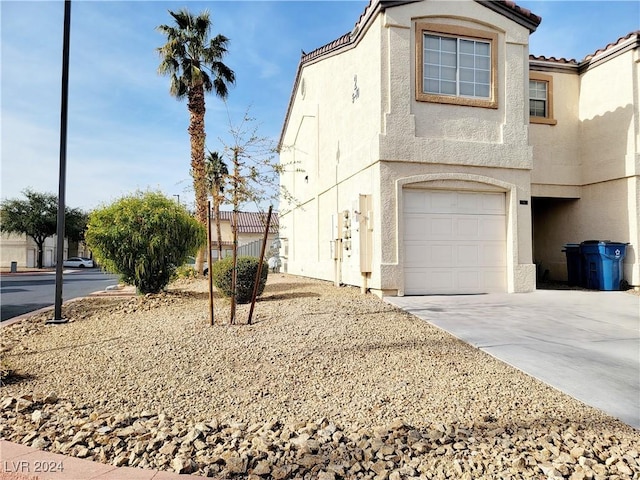 view of front of house with a garage, driveway, a tile roof, and stucco siding