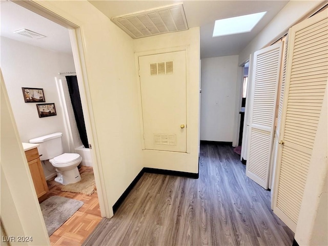 hall with a skylight, visible vents, and wood finished floors