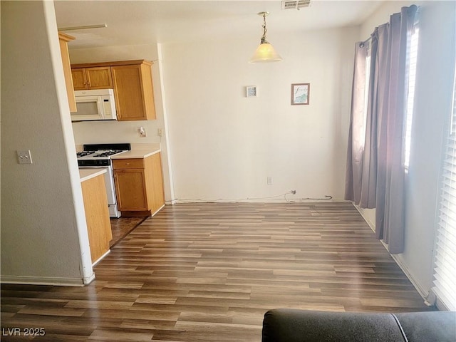 kitchen featuring white appliances, wood finished floors, visible vents, light countertops, and hanging light fixtures