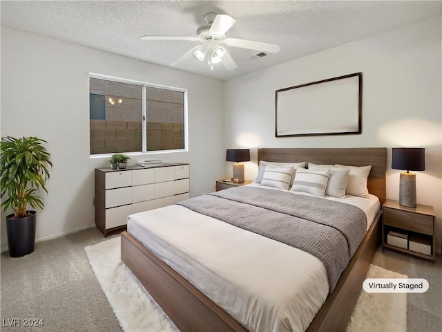 carpeted bedroom with ceiling fan and a textured ceiling