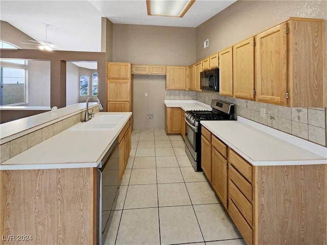 kitchen with sink, stainless steel appliances, tasteful backsplash, a center island with sink, and light tile patterned floors