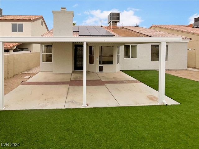 back of property featuring solar panels, a patio, a lawn, and central air condition unit