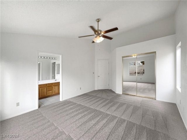 carpeted spare room with a textured ceiling, ceiling fan, and lofted ceiling