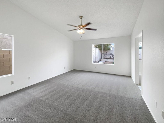 carpeted spare room with a textured ceiling, vaulted ceiling, and ceiling fan