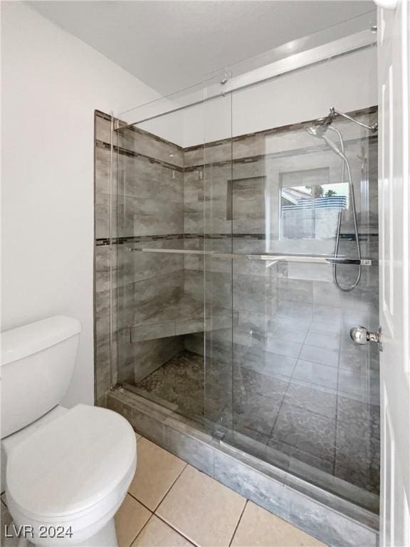 bathroom featuring tile patterned flooring, toilet, and an enclosed shower