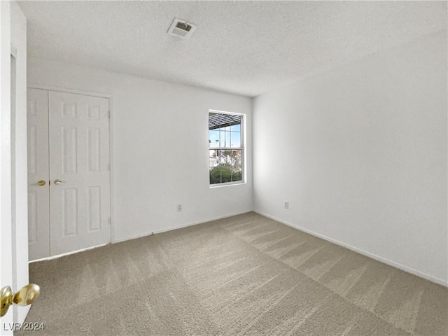 carpeted spare room with a textured ceiling