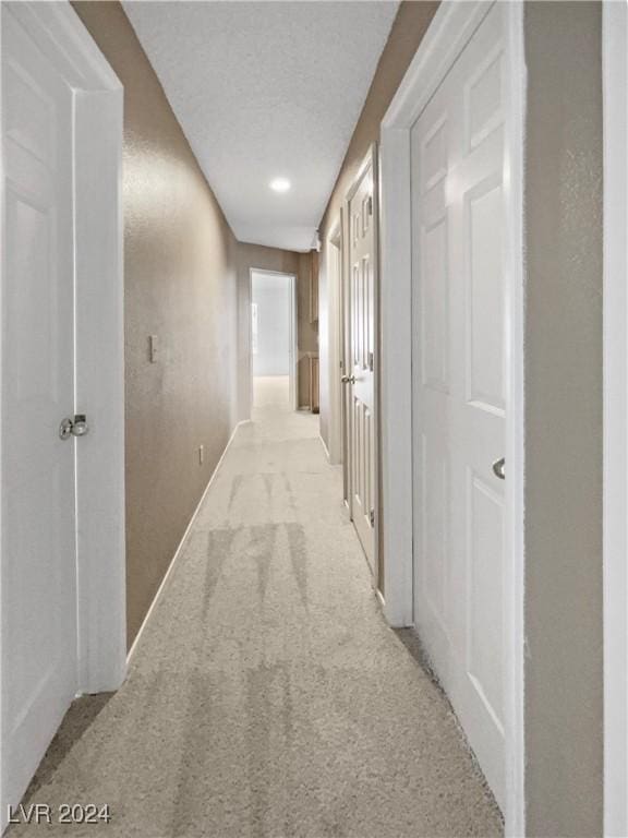 hallway featuring light carpet and a textured ceiling