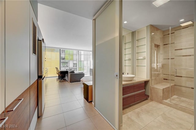 bathroom with tile patterned flooring, vanity, a shower with door, and a wall of windows