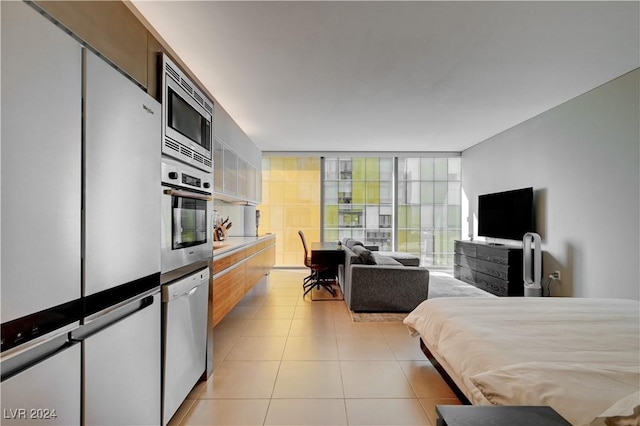 bedroom featuring expansive windows, light tile patterned floors, and white refrigerator