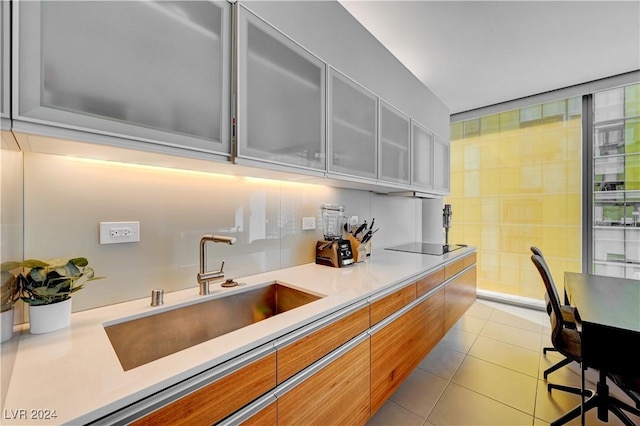 kitchen featuring light tile patterned floors, black electric stovetop, and sink