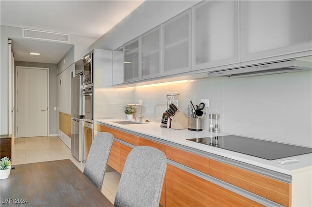 kitchen featuring stainless steel microwave, exhaust hood, black electric stovetop, sink, and tile patterned flooring