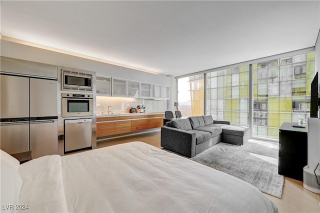 bedroom featuring sink, stainless steel built in fridge, and a wall of windows