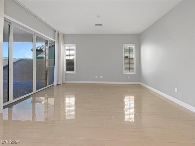 empty room with a wealth of natural light and light tile patterned flooring