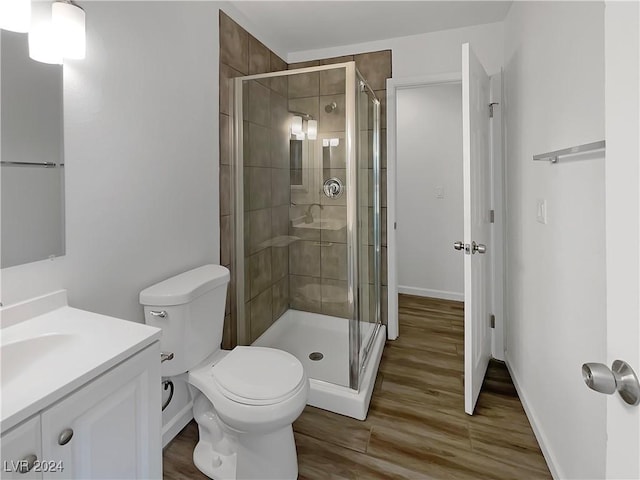 bathroom with hardwood / wood-style floors, vanity, toilet, and a shower with shower door