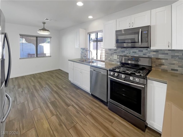 kitchen with pendant lighting, white cabinetry, sink, and appliances with stainless steel finishes