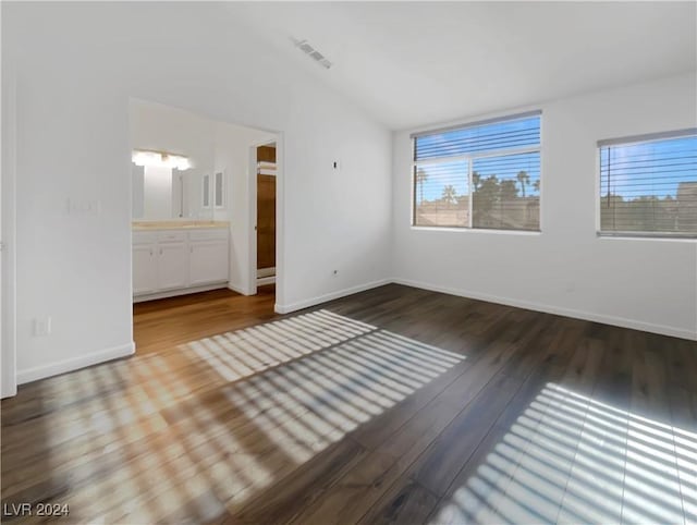 unfurnished bedroom featuring ensuite bathroom, vaulted ceiling, and hardwood / wood-style flooring