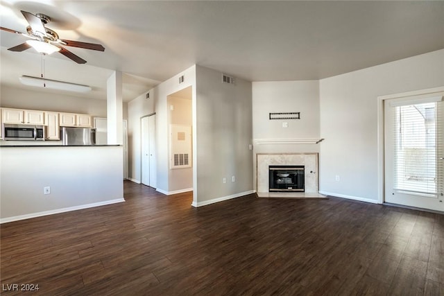 unfurnished living room with ceiling fan, a fireplace, and dark wood-type flooring