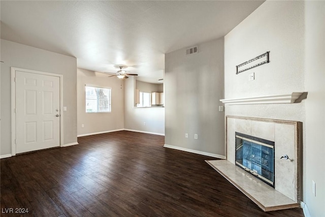 unfurnished living room with ceiling fan, a premium fireplace, and dark wood-type flooring