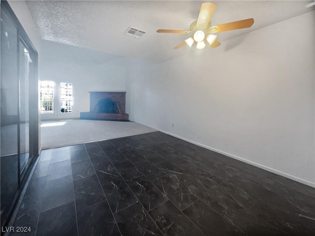 unfurnished living room featuring dark colored carpet, ceiling fan, and a textured ceiling