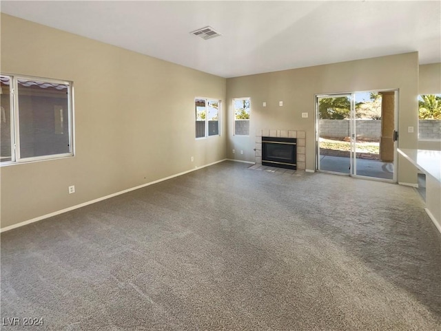 unfurnished living room featuring carpet flooring and a tiled fireplace