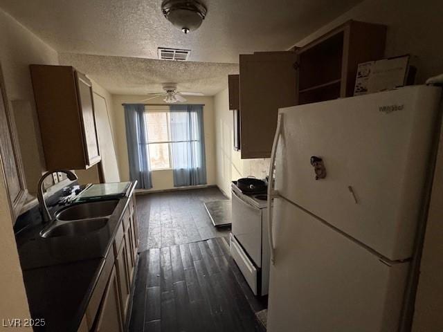 kitchen featuring a textured ceiling, white appliances, ceiling fan, dark wood-type flooring, and sink