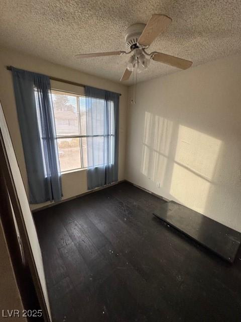 unfurnished room featuring ceiling fan, dark hardwood / wood-style flooring, and a textured ceiling