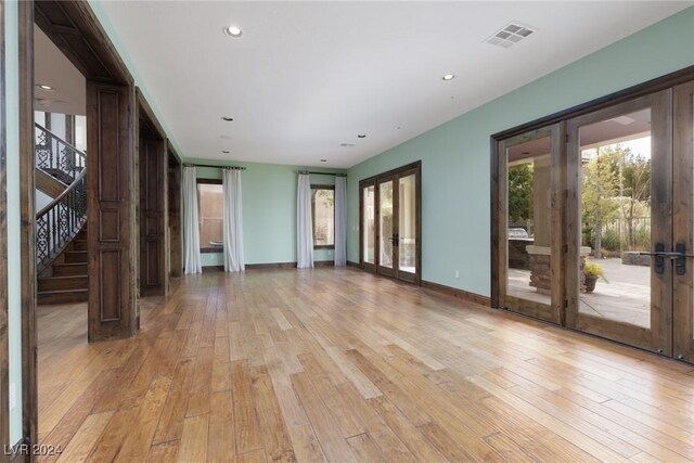 empty room with light wood-type flooring, a wealth of natural light, and french doors