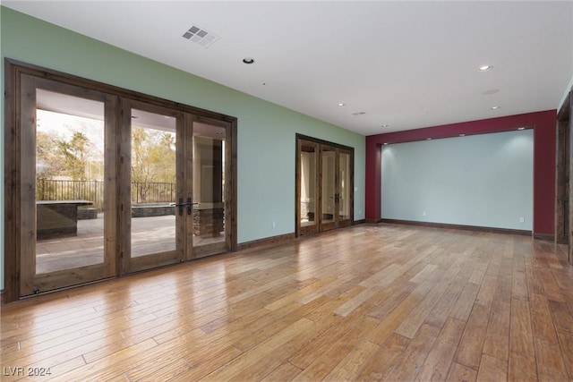 empty room featuring french doors and light wood-type flooring