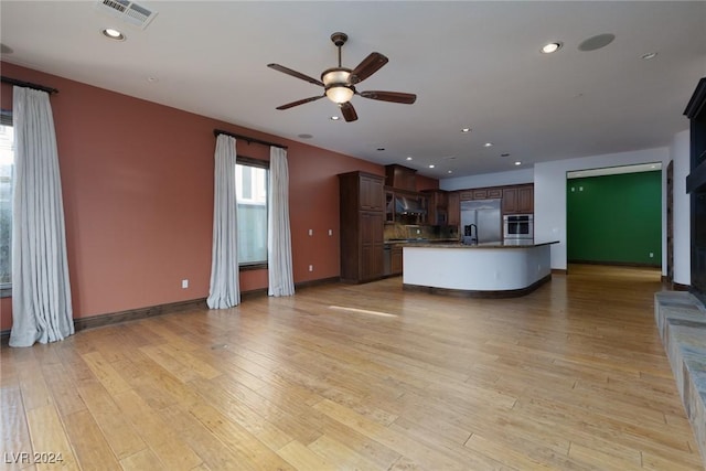 interior space with dark brown cabinets, a kitchen island, light wood-type flooring, and stainless steel appliances