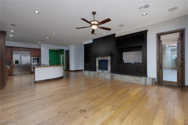 unfurnished living room featuring ceiling fan, light wood-type flooring, and a fireplace