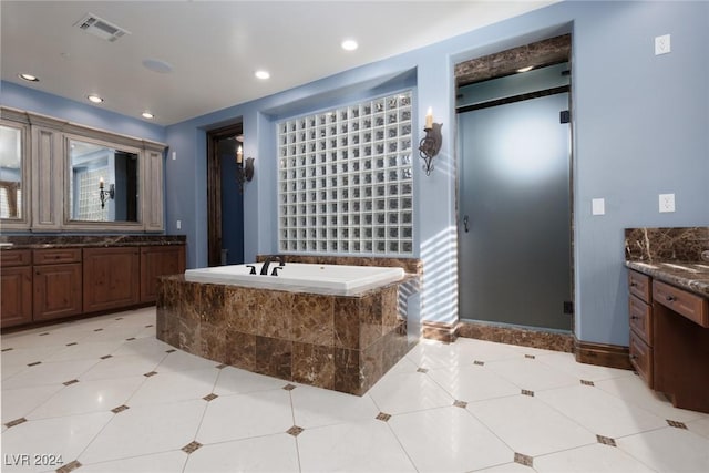 bathroom featuring vanity, a relaxing tiled tub, and tile patterned floors