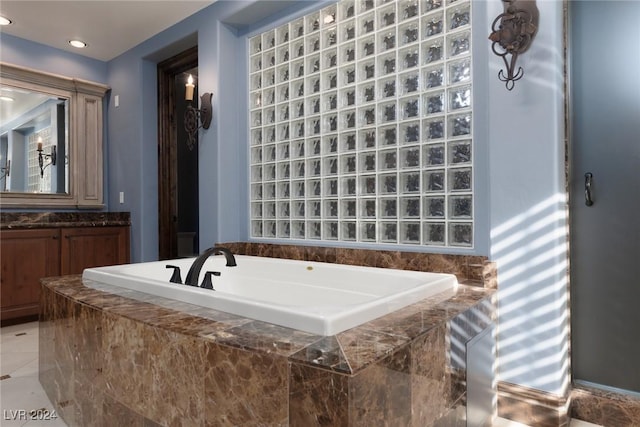 bathroom featuring tiled tub and vanity