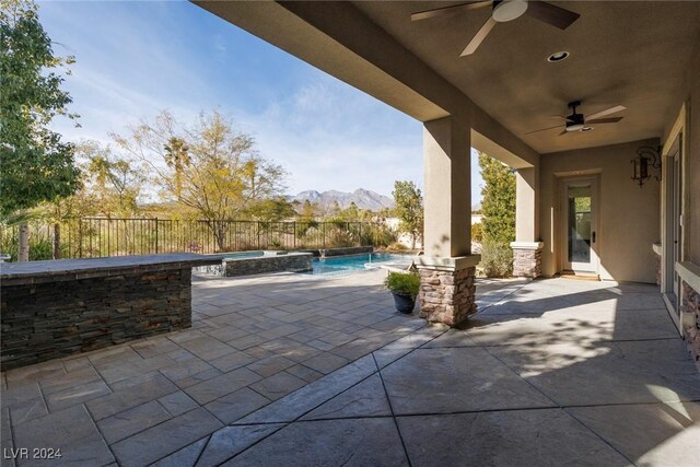 view of patio / terrace featuring a mountain view, ceiling fan, and a pool with hot tub