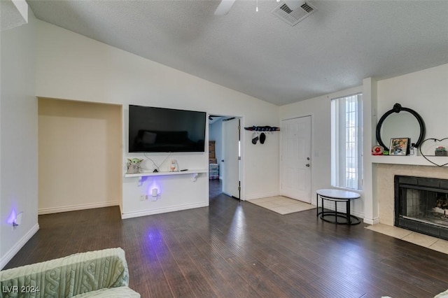 living room with lofted ceiling, hardwood / wood-style floors, a tile fireplace, and a textured ceiling