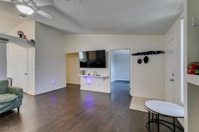 sitting room with ceiling fan, lofted ceiling, dark hardwood / wood-style floors, and a textured ceiling