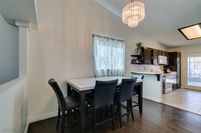 dining space with lofted ceiling, light hardwood / wood-style flooring, and an inviting chandelier