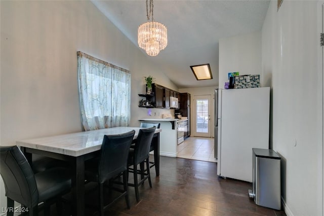 dining space with lofted ceiling, dark hardwood / wood-style floors, and a notable chandelier